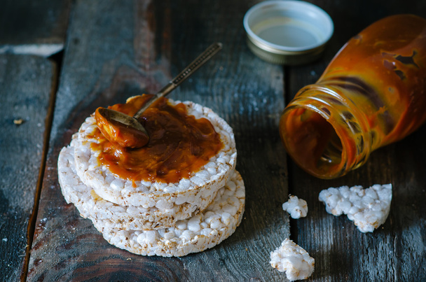 Rice cakes with salted caramel on old wooden background - Foto, afbeelding