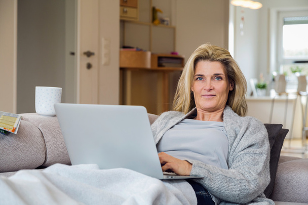  donna seduta sul divano a casa a lavorare
 - Foto, immagini
