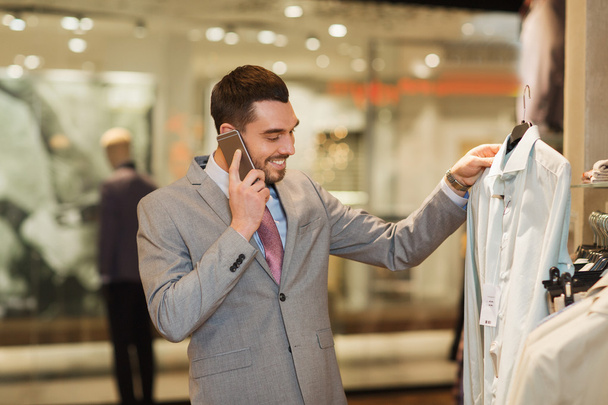 happy man calling on smartphone at clothing store - Фото, изображение