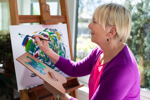 Glückliche ältere Frau malt zum Spaß zu Hause - Foto, Bild