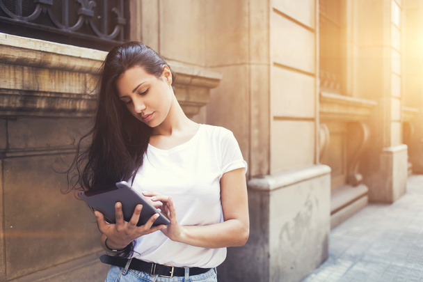 Beautiful hipster girl is using on touch pad in urban setting - Foto, afbeelding