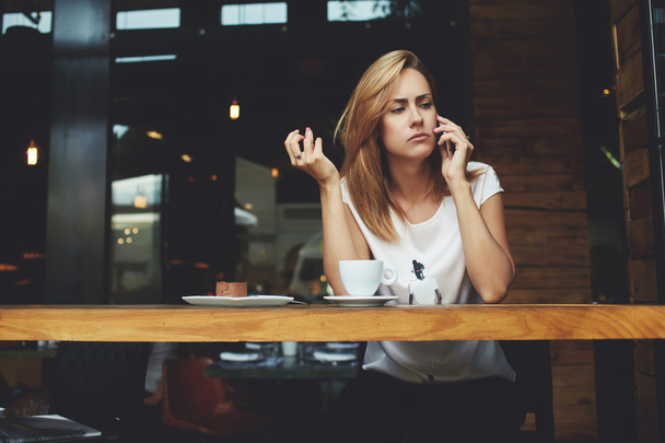 Concerned female have in bad mood tis talking on cell telephone while sitting alone in coffee shop  - 写真・画像