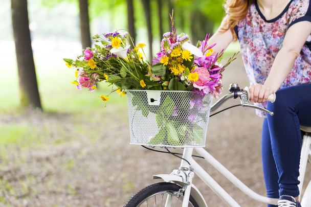 Woman holding a vintage bicycle with flowers - 写真・画像