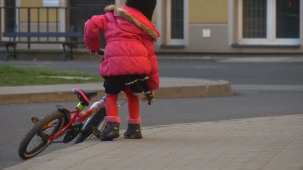 Kid is Walking Toward a Bike Sits Riding the Bike Awkwardly by City Street in Opole Poland Child is Riding by a Courtyard of a House Sunny Day Spring - Кадры, видео