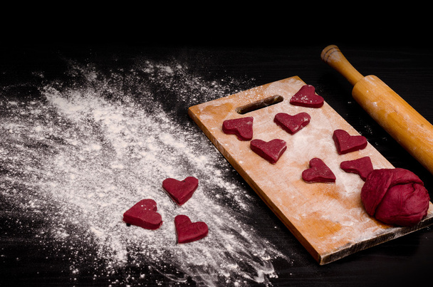 Biscuit coeur rouge et un morceau de pâte sur la planche en bois, cuisson pour la Saint-Valentin
 - Photo, image