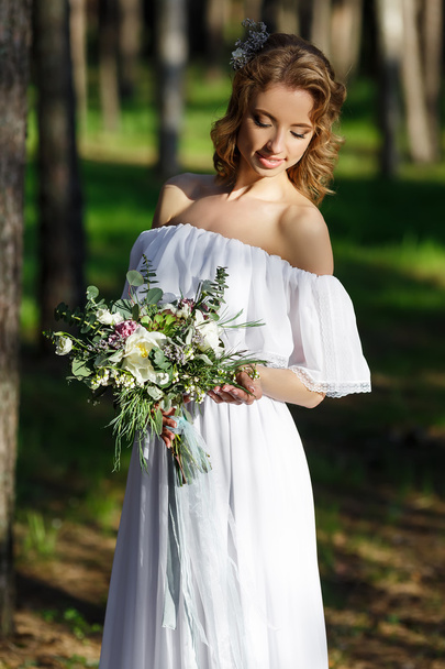 Bride standing and holding a wedding bouquet in hand - Fotoğraf, Görsel