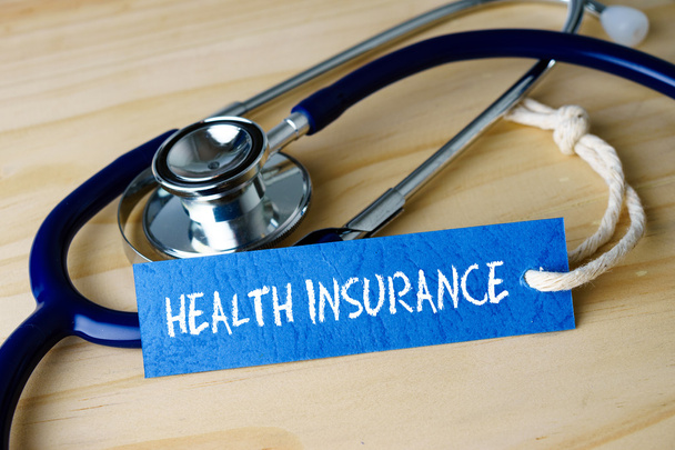 Image with HEALTH INSURANCE words and stethoscope on wooden background. - Фото, зображення
