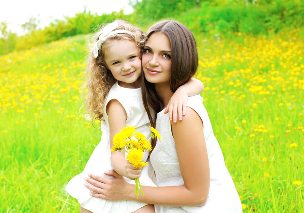 Happy mother and daughter child together with yellow dandelion f - Zdjęcie, obraz