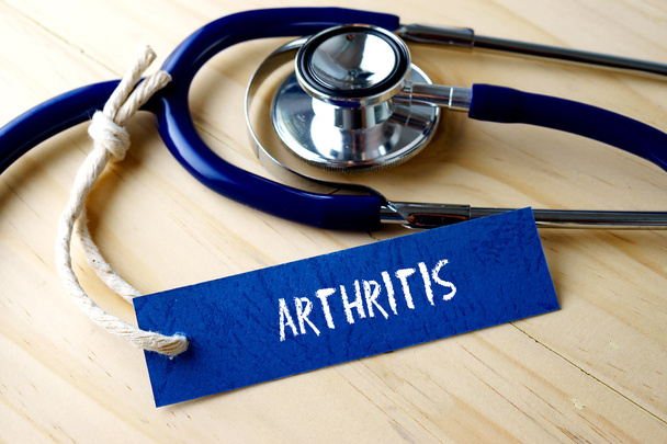 Artrit kelime yazıldı etiket etiket ve ahşap arka plan üzerinde stetoskop. - Fotoğraf, Görsel