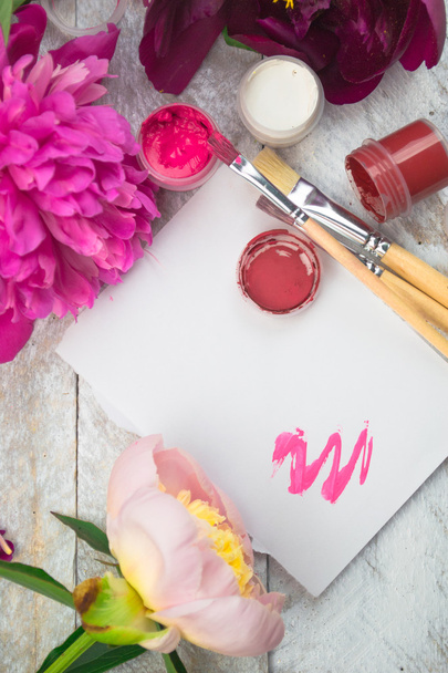 Workspace. Watercolor, paintbrush and pink peonies isolated on white background. Overhead view. Flat lay, top view - Fotografie, Obrázek