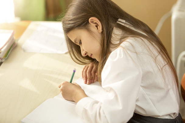 Geconcentreerde schoolmeisje huiswerk thuis - Foto, afbeelding