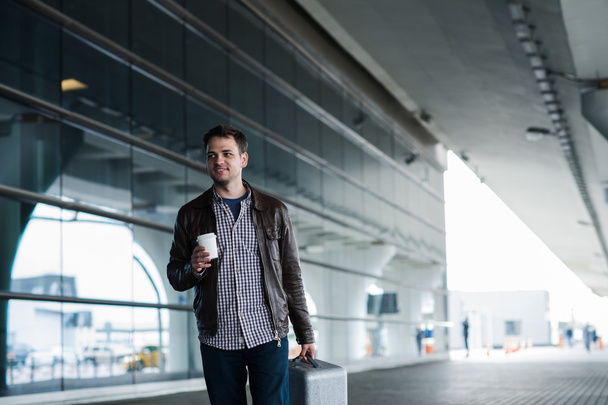 袋を押しながら一杯のコーヒーと歩いて空港の男 - 写真・画像
