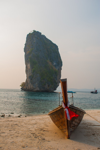 Длинная хвостовая лодка на пляже с известняковыми скалами. Закат, укрощение острова. Фабби, Таиланд
. - Фото, изображение
