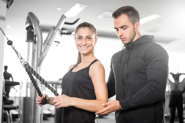 Entrenador de fitness personal con su cliente en el gimnasio
. - Foto, Imagen