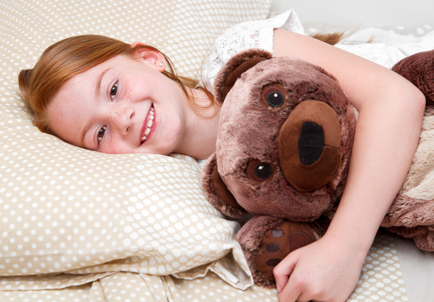 Little girl in bed hugging  the teddy bear - Fotoğraf, Görsel