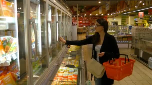 Mujer joven comprando productos lácteos o refrigerados en el supermercado
 - Metraje, vídeo