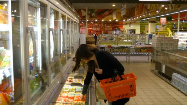 genç kadın satın alma süt veya süpermarkette buzdolabında yiyecek - Video