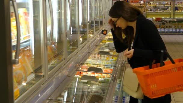Mujer joven comprando productos lácteos o refrigerados en el supermercado
 - Imágenes, Vídeo