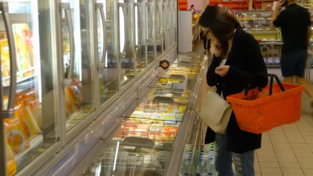 genç kadın satın alma süt veya süpermarkette buzdolabında yiyecek - Video, Çekim