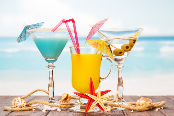 Two cocktails,  glass  juice, starfish and shells on sea background. - Fotografie, Obrázek