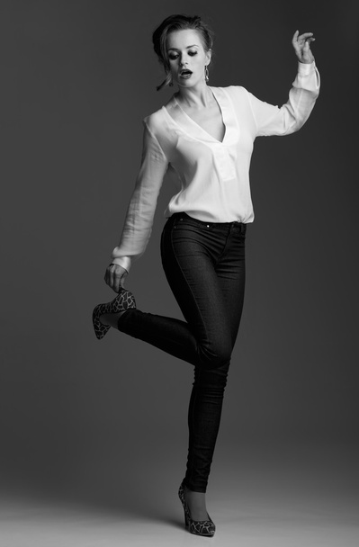 Modern elegant woman adjusting shoe against grey background - Foto, Imagem