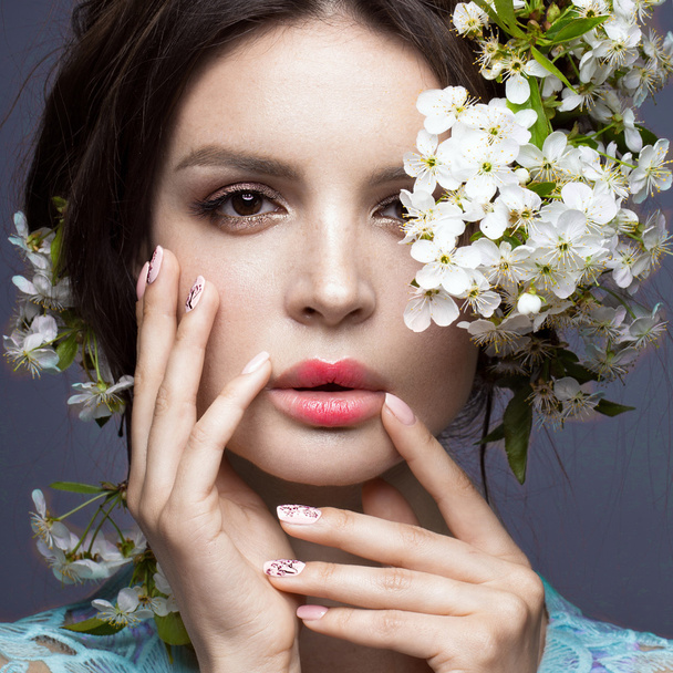 Beautiful brunette girl in blue dress with a gentle romantic make-up, pink lips and flowers. The beauty of the face. - Foto, Imagem