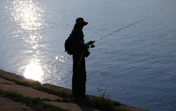 Рыбак на берегу реки при солнечном свете
 - Фото, изображение