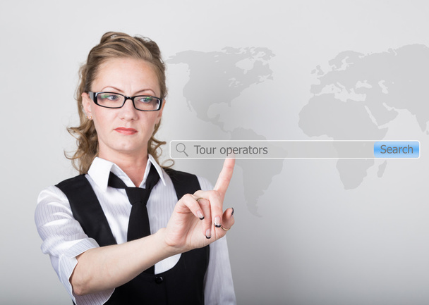 tour operators written in search bar on virtual screen. Internet technologies in business and home. woman in business suit and tie, presses a finger on a virtual screen - Photo, Image