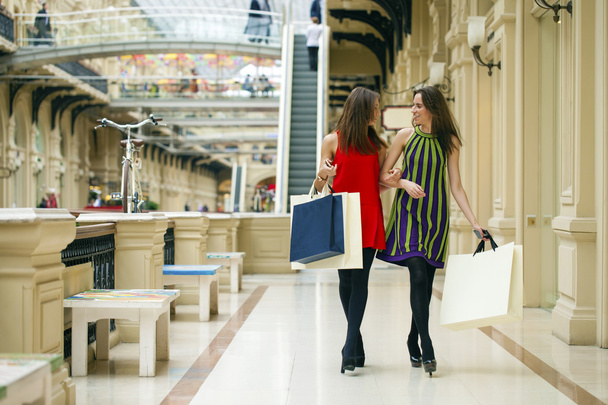 Две девушки на прогулке по магазинам по торговому центру с сумками
 - Фото, изображение
