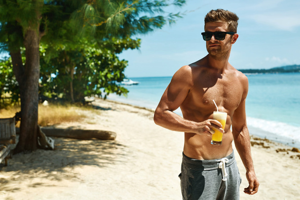 Man With Muscular Body Drinking Healthy Drink On Beach. Summer - Foto, Imagen