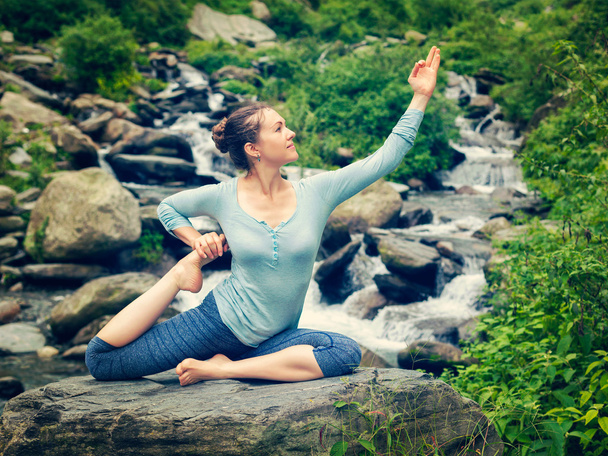 Sorty fit woman doing yoga asana outdoors at tropical waterfall - Foto, imagen