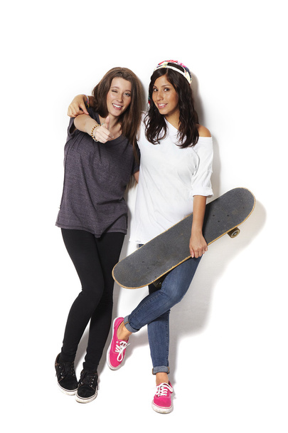 Two young skateboarding girl friends smiling - isolated over white background. - Φωτογραφία, εικόνα