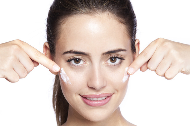 Portrait of beautiful woman applying cream on face - Foto, Imagem