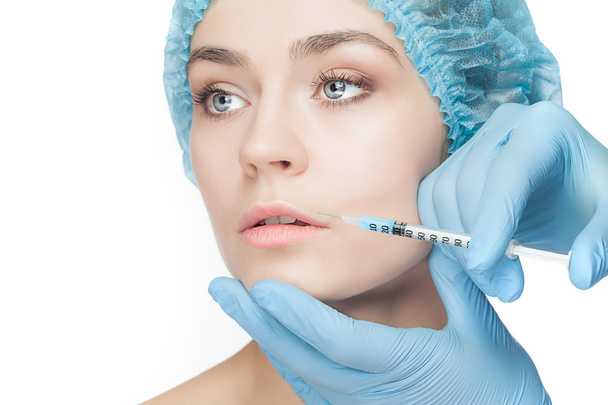 Attractive woman at plastic surgery with syringe in her face - Foto, Imagen