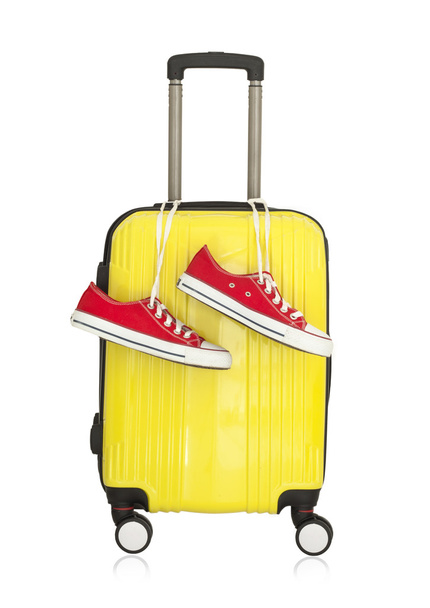 Κίτρινο βαλίτσα με ζευγάρι κόκκινα αθλητικά παπούτσια - Φωτογραφία, εικόνα