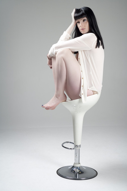 Jeune femme assise sur un tabouret blanc
 - Photo, image