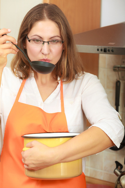 Woman with ladle and pot in kitchen - Zdjęcie, obraz