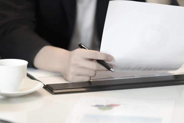 Близко к руке деловая женщина держит ручку и финансовый документ
 - Фото, изображение