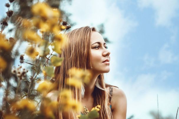 Beautiful, natural girl among yellow flowers and clouds in the profile. - Fotoğraf, Görsel