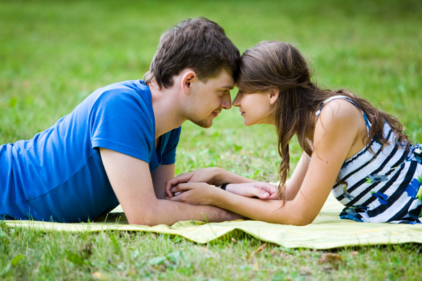 Mulher feliz e seu namorado descansando no gramado verde no parque
 - Foto, Imagem