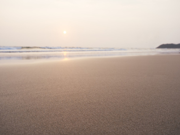 Παραλία με άμμο και η θάλασσα με ηλιοβασίλεμα - Φωτογραφία, εικόνα
