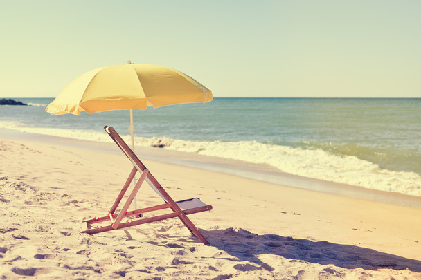 Yellow umbrella and wooden chair on Atlantic sandy beach - Fotografie, Obrázek