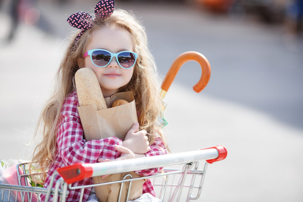 Little girl sitting in shopping trolley - Zdjęcie, obraz