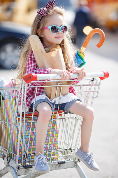 Little girl sitting in shopping trolley - Фото, зображення