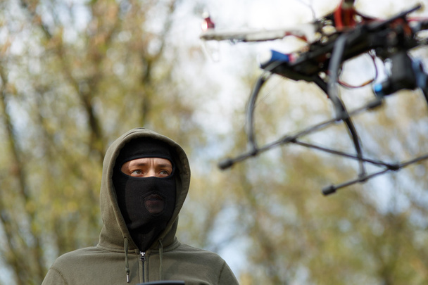 Man in mask operating a drone with remote control. - Foto, imagen