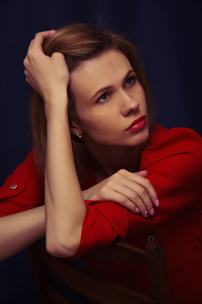Kırmızı bluz bir sandalyede oturan güzel genç kız - Fotoğraf, Görsel