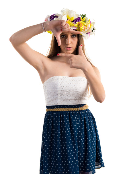 Woman with crown of flowers focusing with her fingers - Photo, Image