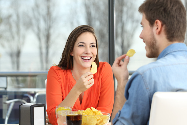 Couple talking and eating chip potatoes - 写真・画像