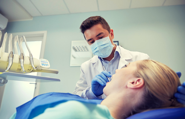 male dentist in mask checking female patient teeth - Photo, Image
