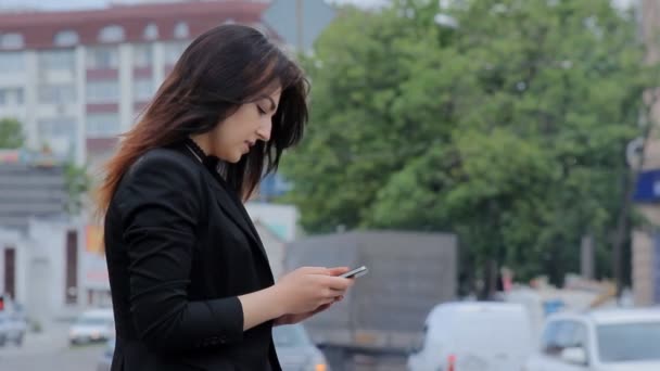 Vrouw met smartphone lopen in de stad bij zonsondergang. Steadicam schot - Video